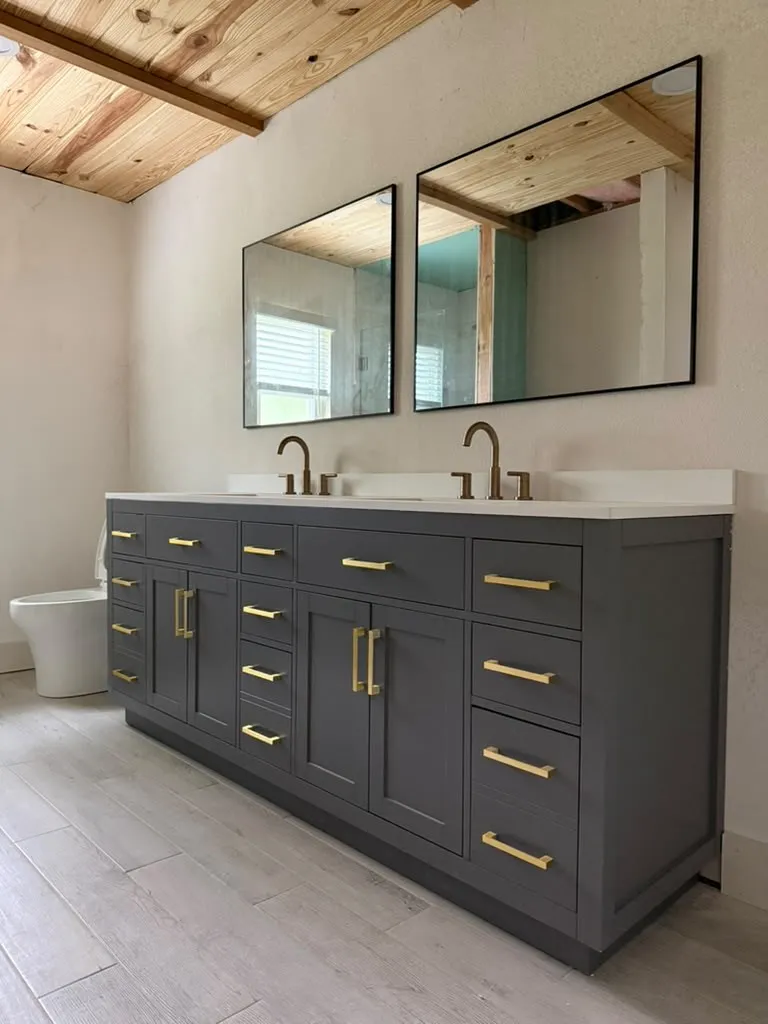Dual vanity with a white countertop, dark cabinetry, and gold-finish hardware