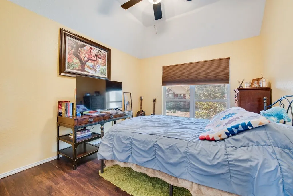 Bedroom with a ceiling fan, dark wood finished floors, and baseboards