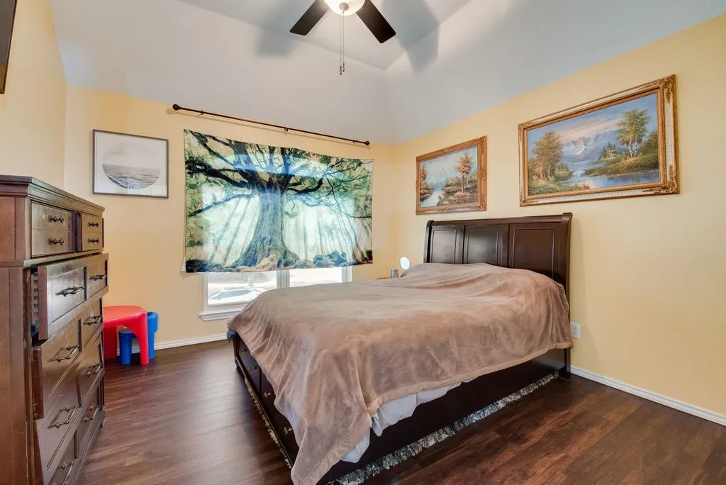 Bedroom featuring ceiling fan, baseboards, and dark wood-style flooring