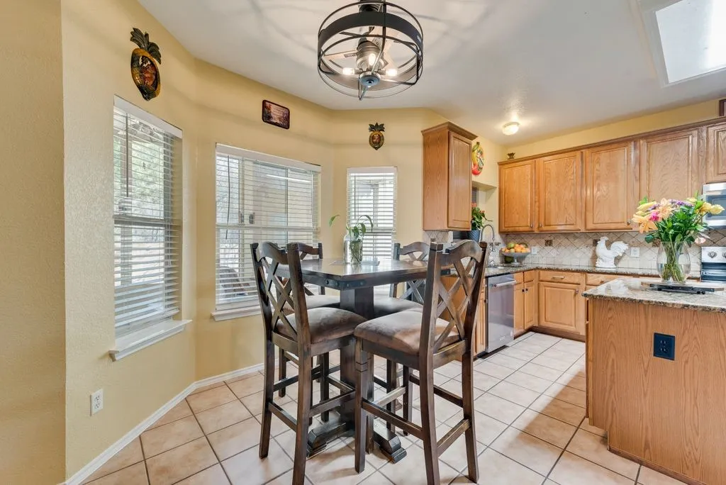 Kitchen with stainless steel appliances, light tile patterned flooring, light stone counters, and decorative backsplash