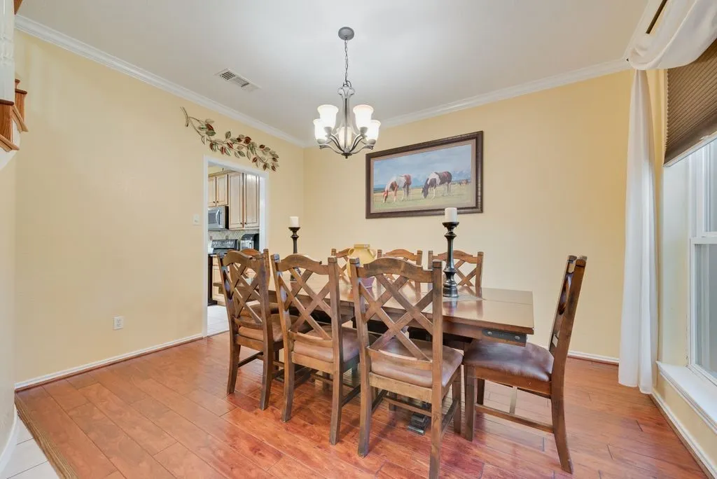 Dining room featuring a chandelier, visible vents, light wood-style floors, baseboards, and crown molding