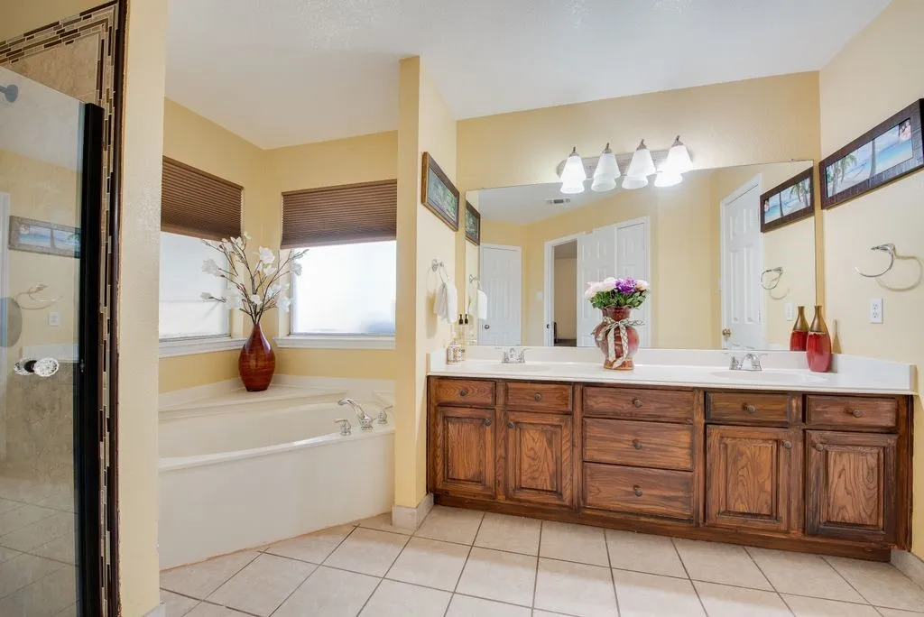 Full bathroom featuring tile patterned flooring, double vanity, a sink, and a bath