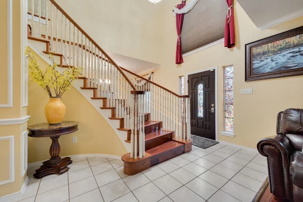 Tiled entrance foyer with a high ceiling, stairs, baseboards, and ornamental molding