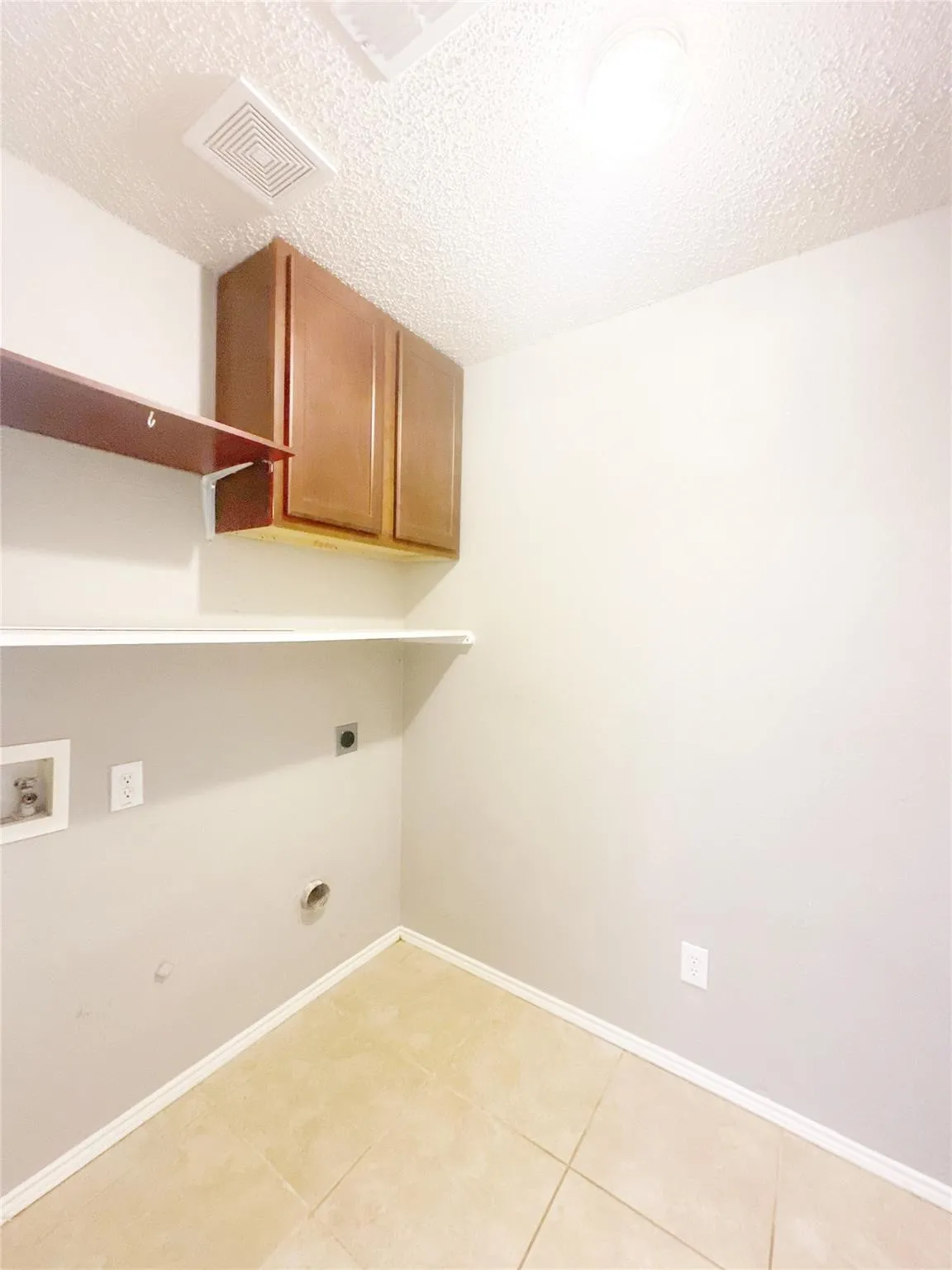Utility room with tile flooring, wall-mounted cabinetry, and an integrated shelf system
