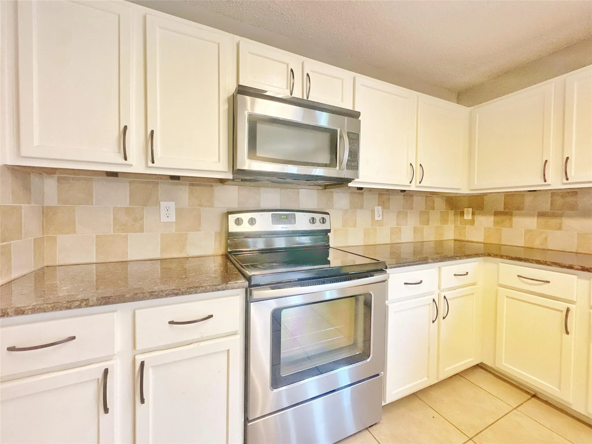 White cabinetry with dark-finish hardware, stainless steel range, and built-in microwave