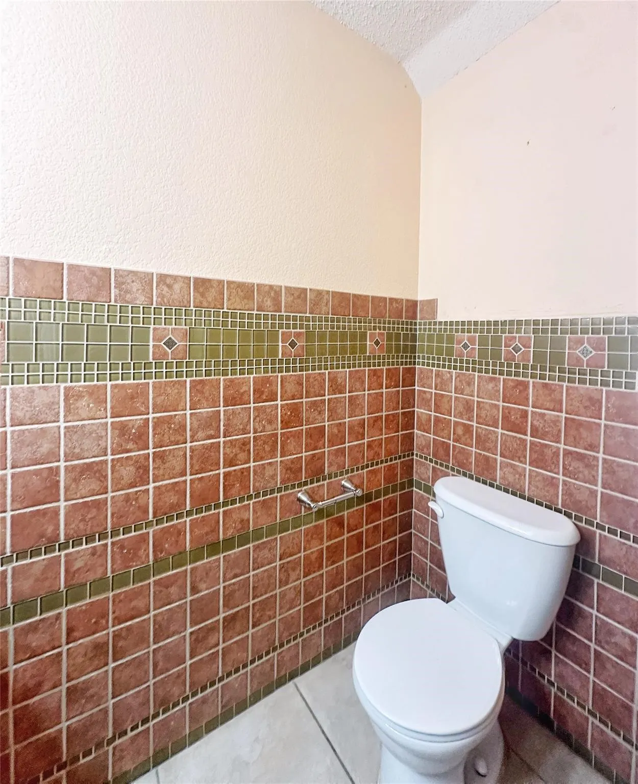 Ceramic tile wainscoting featuring a decorative mosaic border