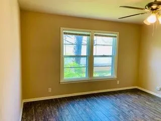 Wood-finish flooring, dual windows, and a ceiling fan with integrated lighting