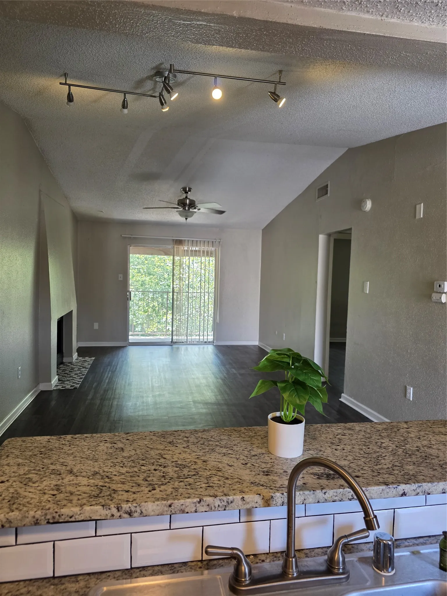 Kitchen counter featuring a granite-style surface, white subway tile backsplash, and a dual-basin sink with a bronze-finish faucet