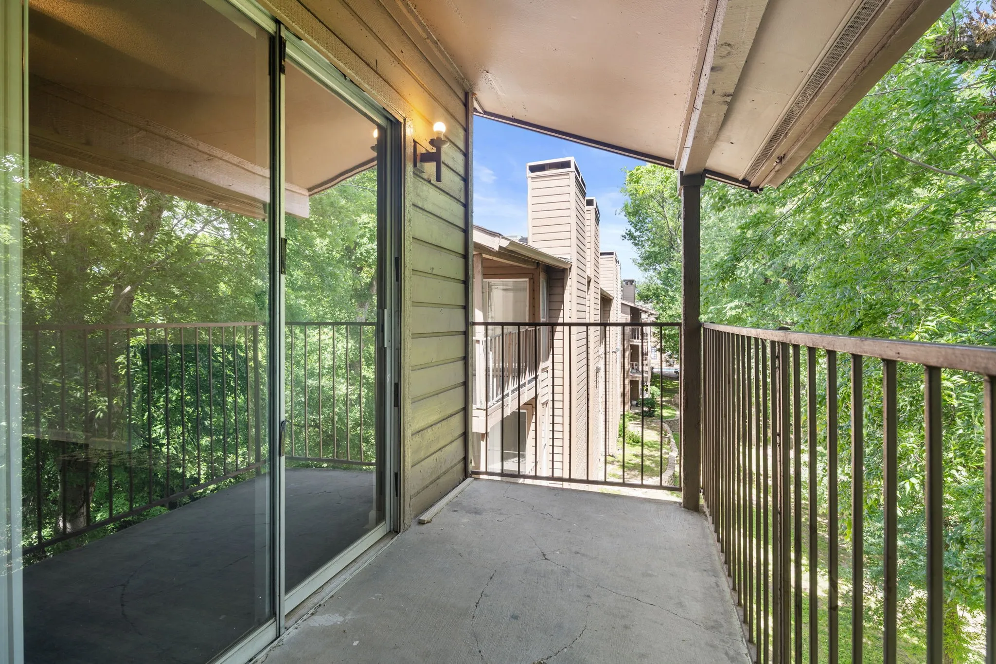 Balcony featuring a concrete surface, metal railing, and sliding glass door