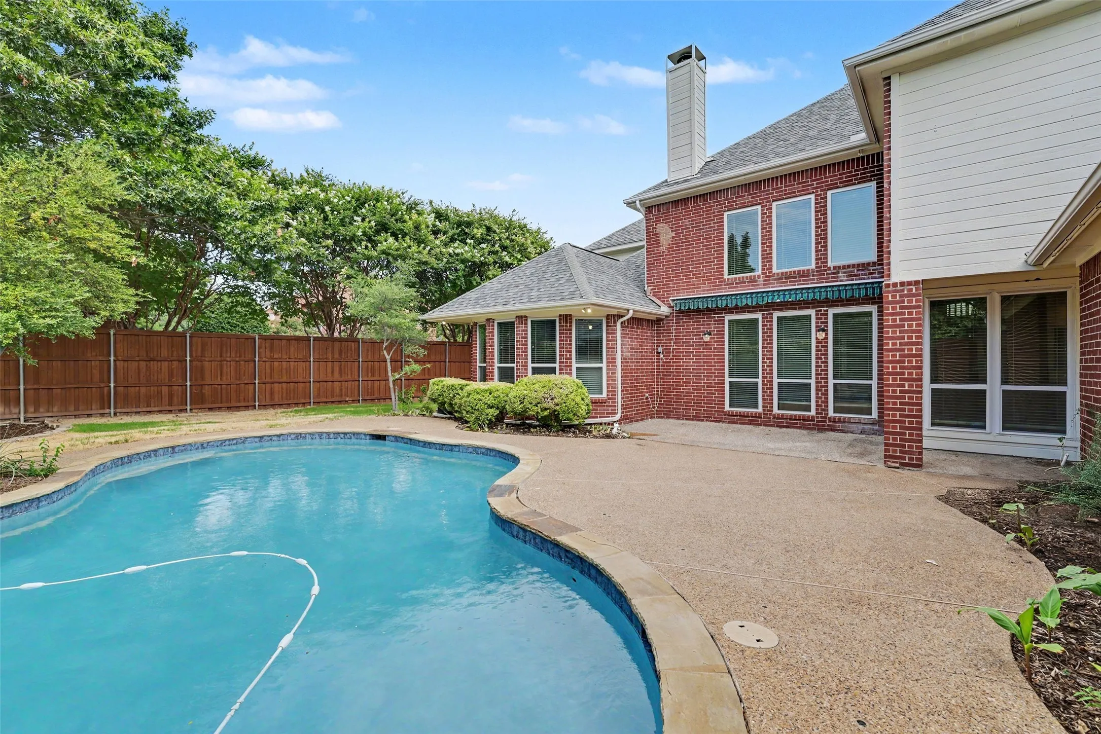 Sparkling resort-style swimming pool with curved design and concrete decking, anchoring an expansive backyard retreat