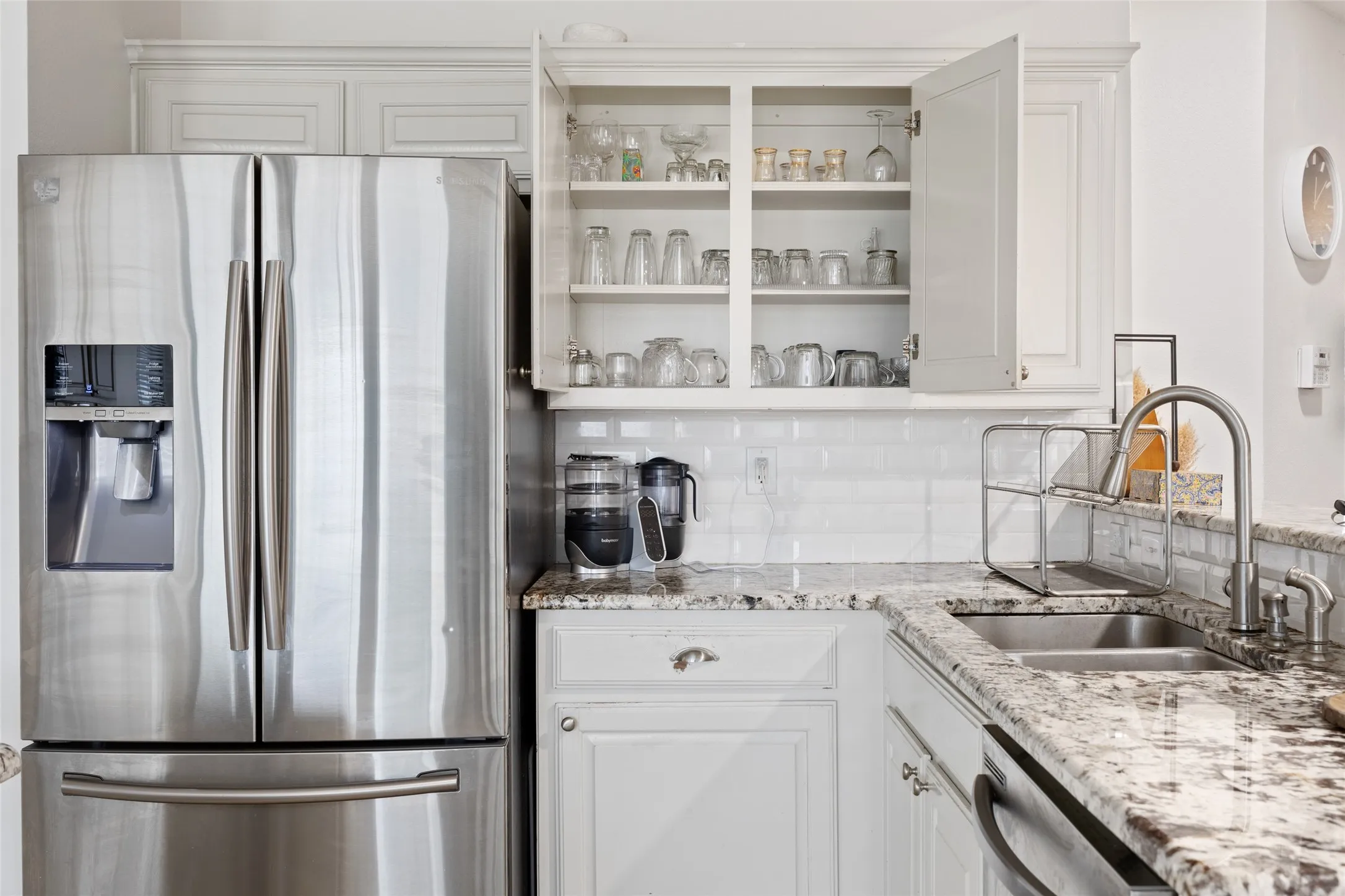 Stainless steel French door refrigerator, white shaker-style cabinetry, double basin stainless steel sink, gooseneck faucet, and white subway tile backsplash