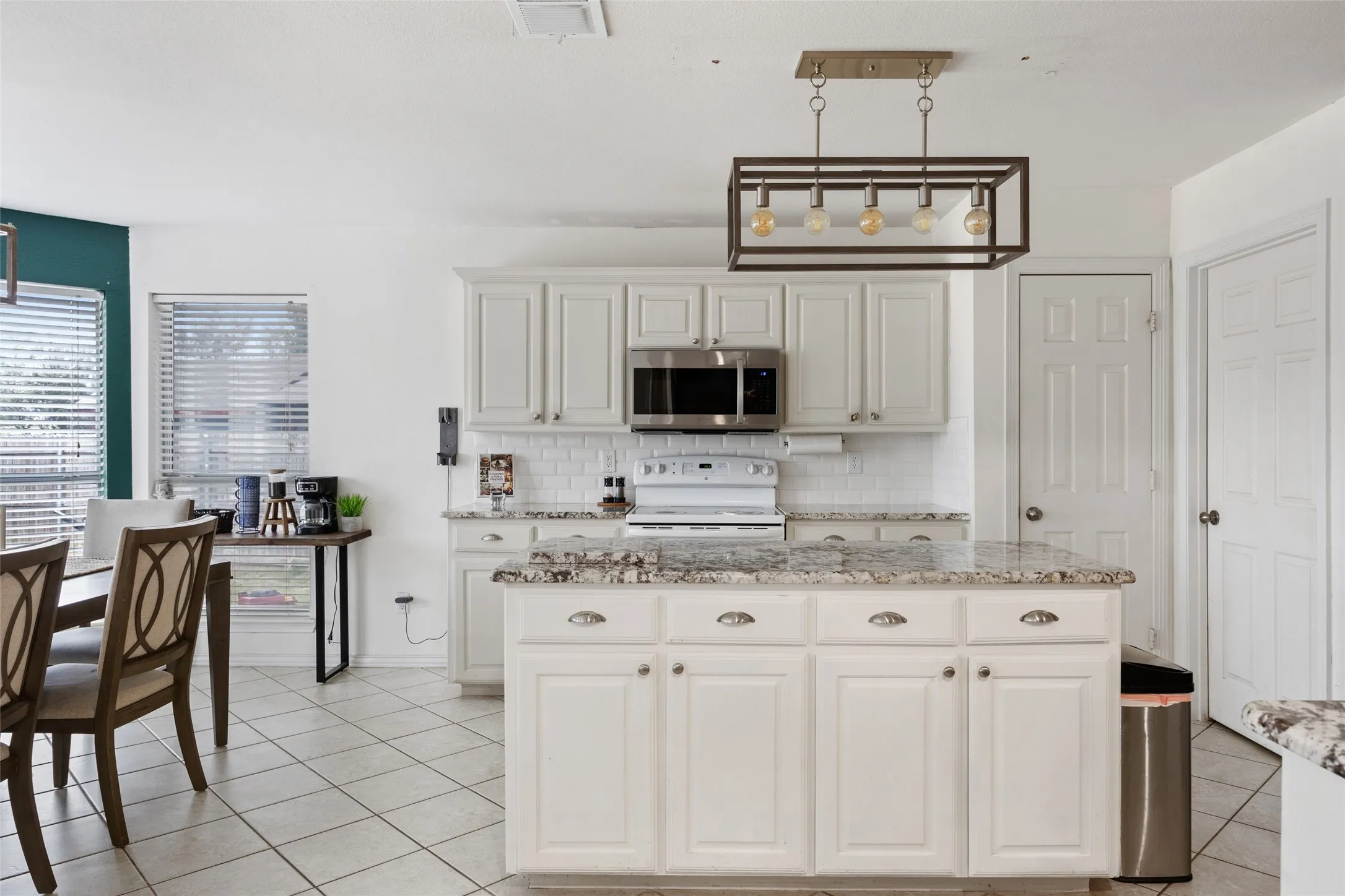 Kitchen featuring a center island, light-toned cabinetry, subway tile backsplash, and stainless steel appliances