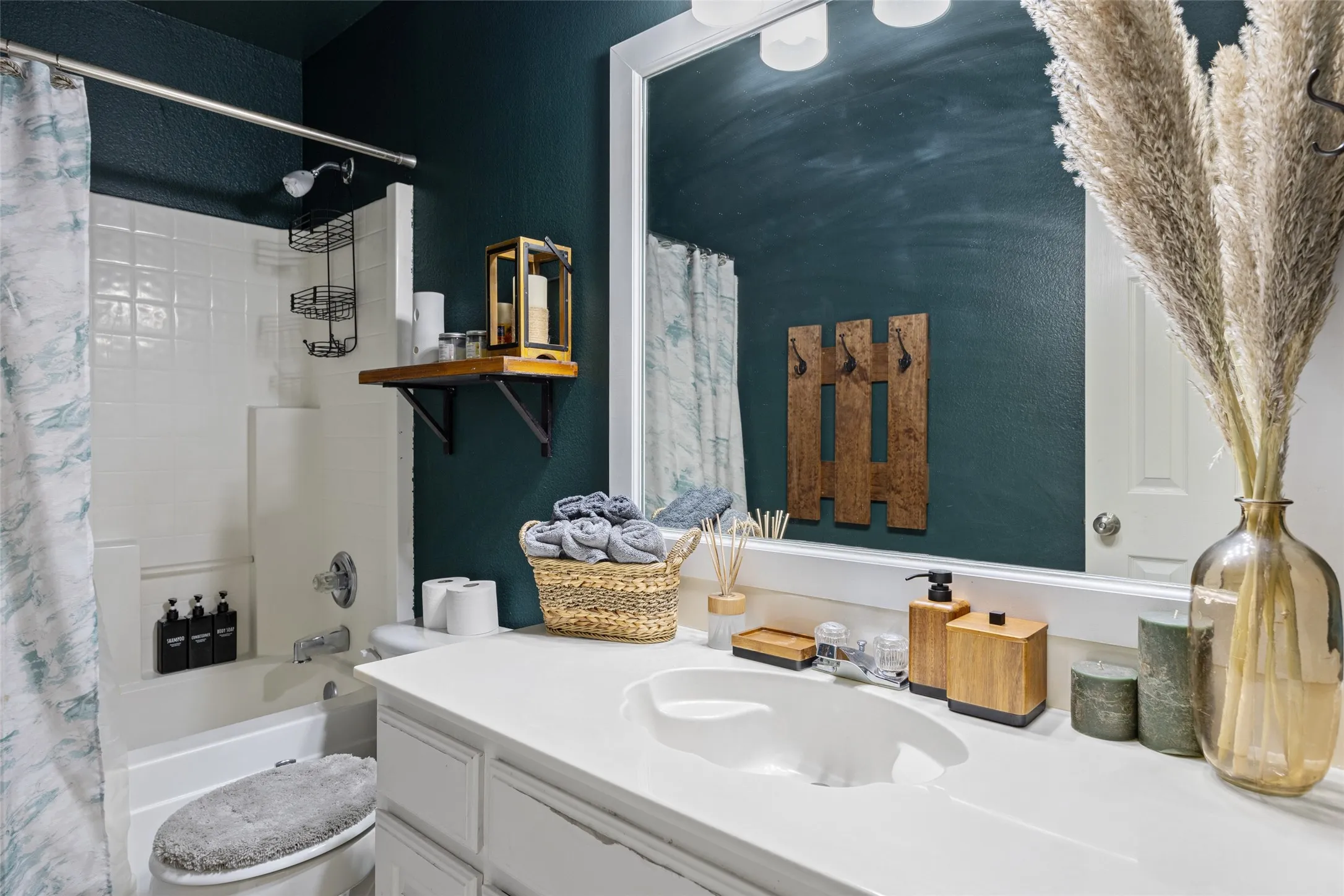 White vanity with an integrated sink, large framed mirror, and a built-in bathtub with white tile surround