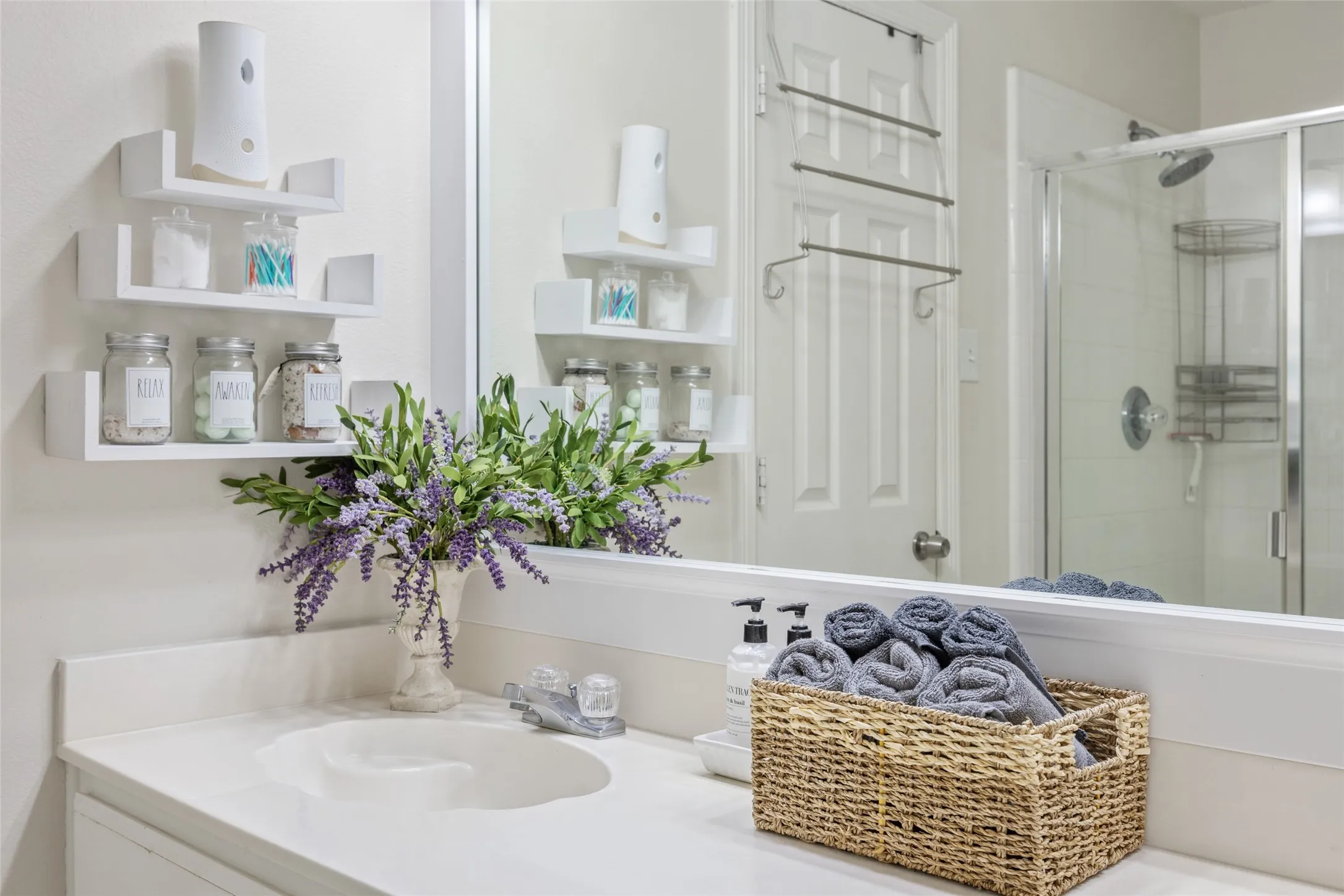 White vanity with an integrated sink, polished chrome faucet, and a large wall-mounted mirror