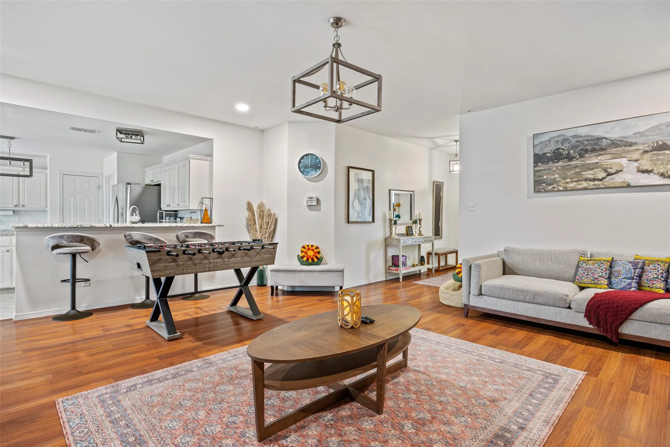Hardwood-style flooring throughout, recessed lighting, and a kitchen pass-through with breakfast bar