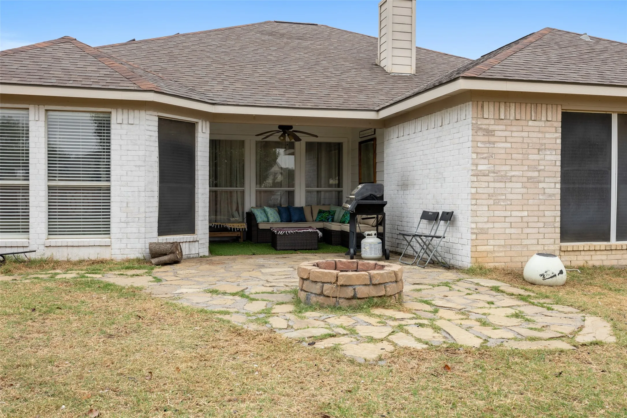 Covered patio with ceiling fan, flagstone patio, and brick fire pit