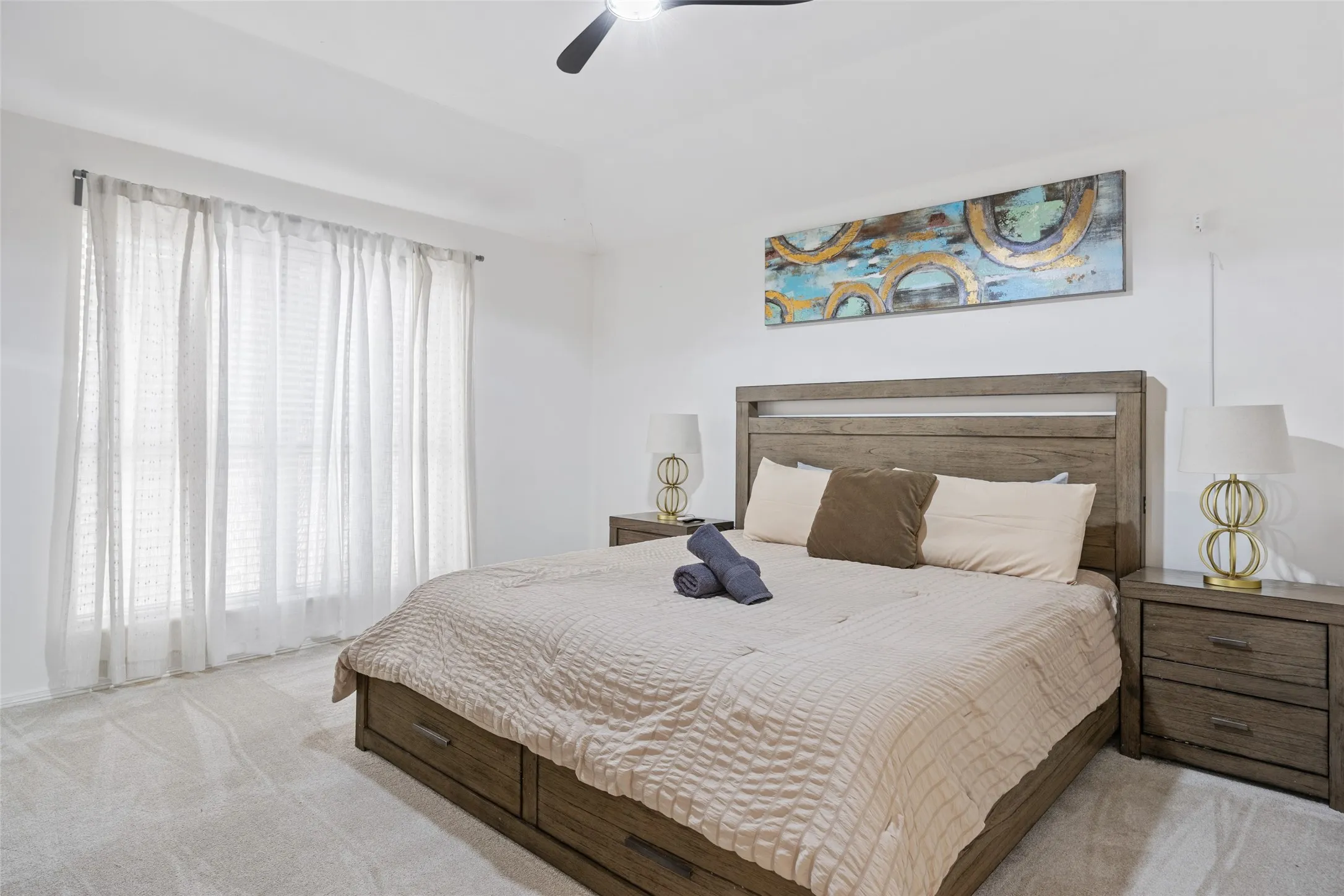 Serene primary bedroom showcasing a wood-finish platform bed with horizontal slat detailing, soft neutral bedding, and dual nightstands with integrated lighting