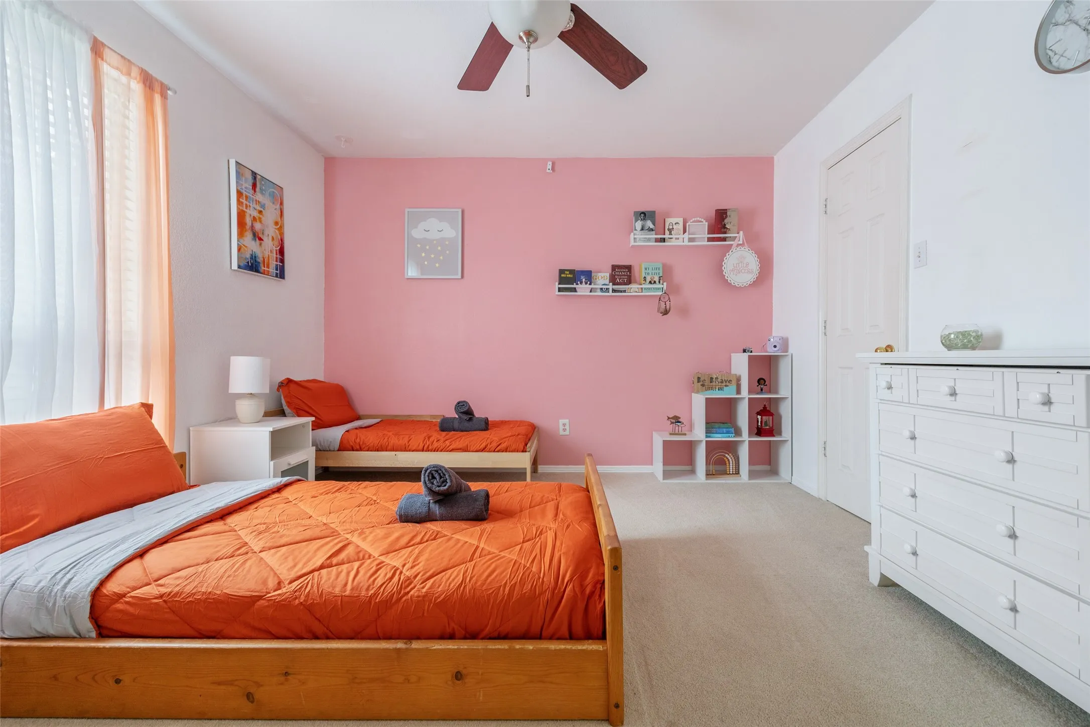 Carpeted room featuring a ceiling fan, a white paneled door, and a built-in shelving unit