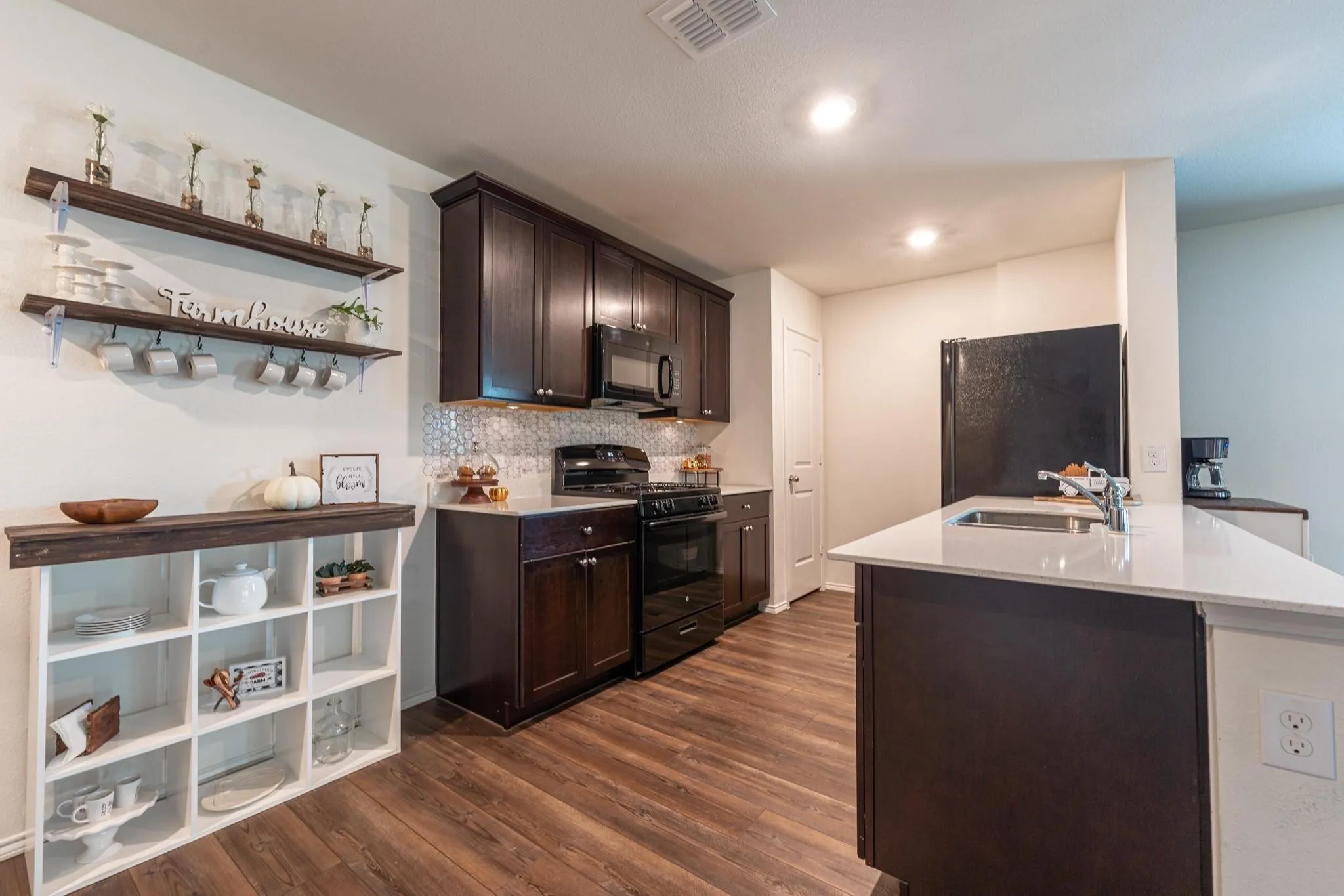 Kitchen featuring dark brown cabinets, sink, dark hardwood / wood-style flooring, and black appliances