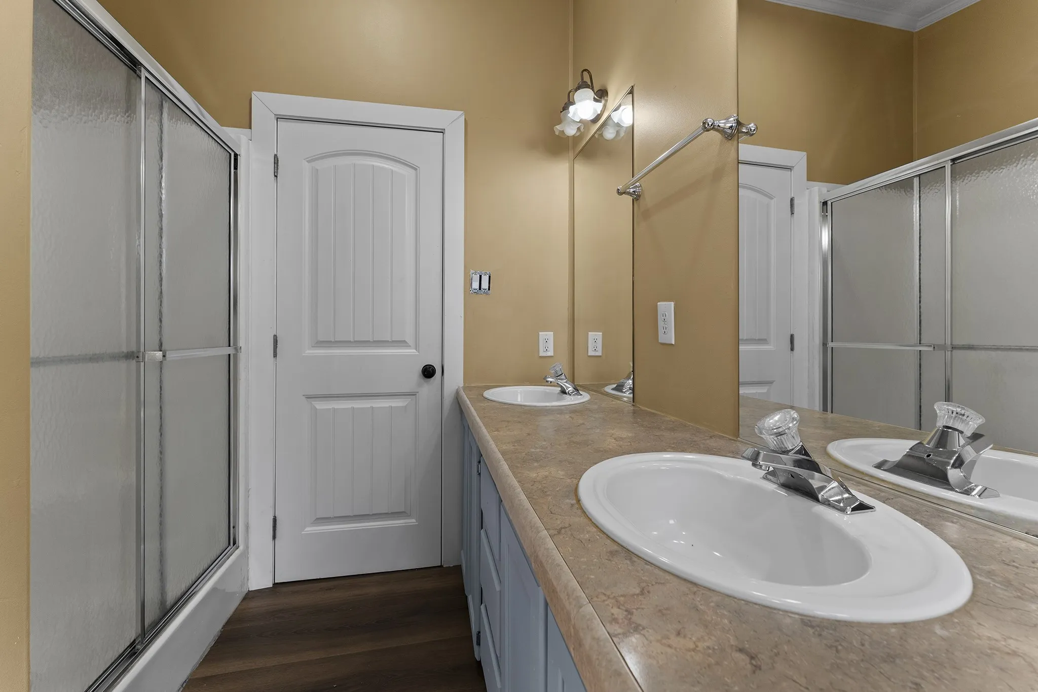 Primary bathroom featuring a spacious vanity with generous counter space, a large wall mirror, ample cabinetry, and a separate enclosed shower.