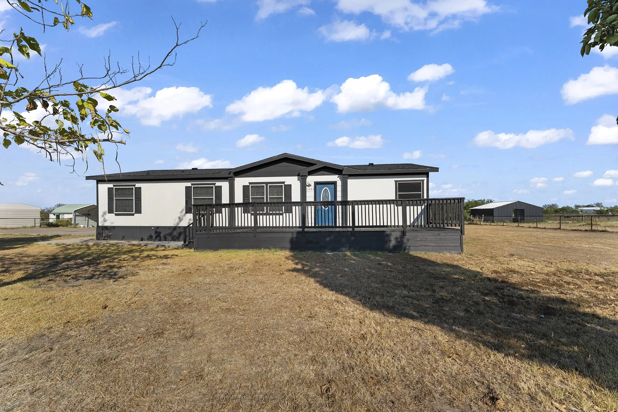 Front exterior featuring a spacious covered porch and an expansive yard with plenty of open space.