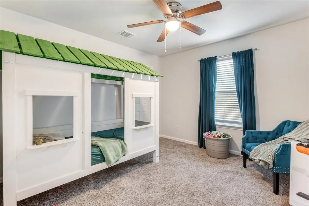 Carpeted room featuring a ceiling fan, a window with blinds, and white walls