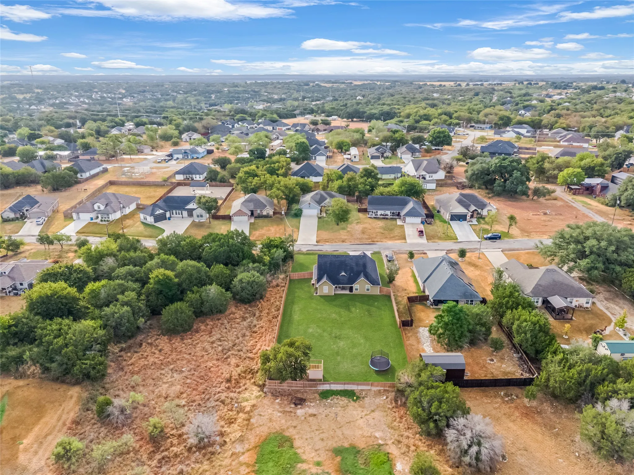 Aerial perspective of a residential community featuring single-family homes, mature trees, and varying lot sizes