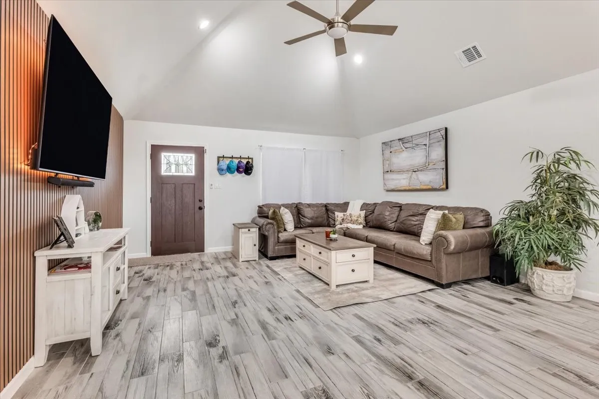 Vaulted ceiling with a ceiling fan, recessed lighting, wood-finish flooring, and a decorative front entry door