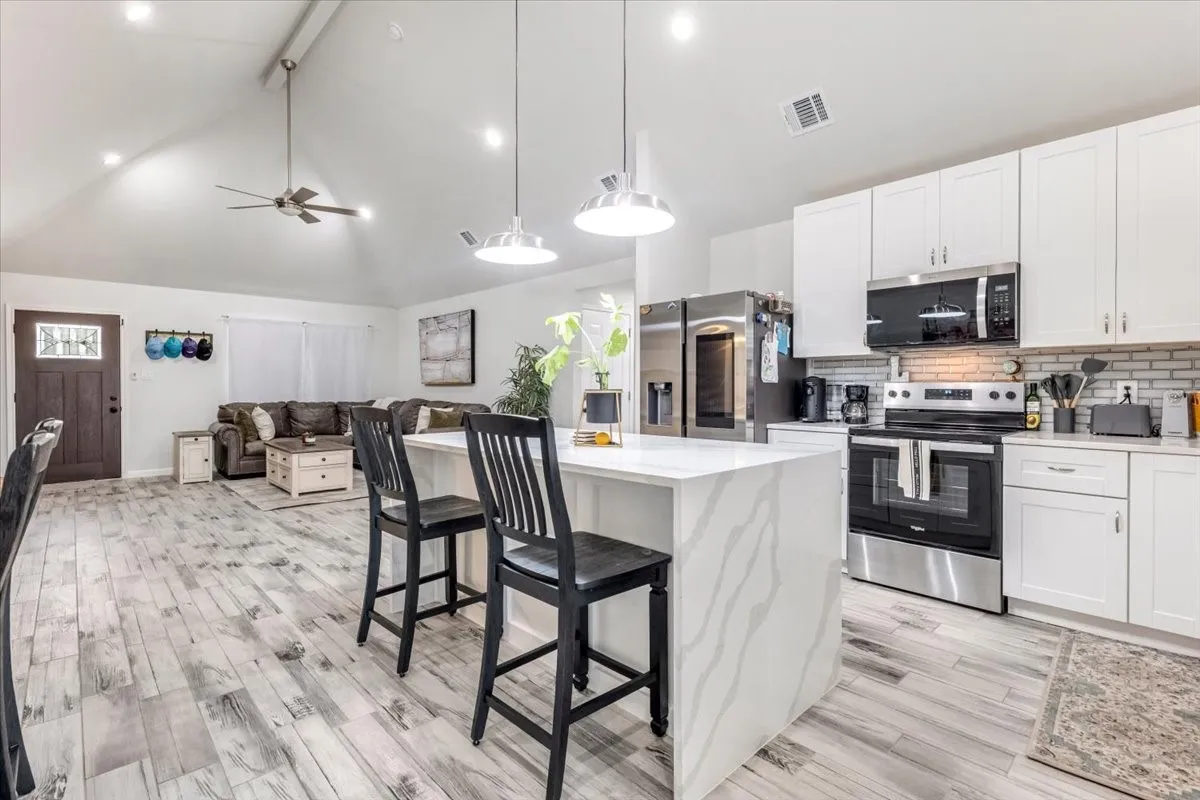 Open-concept interior featuring wood-finish flooring, a vaulted ceiling, and recessed lighting