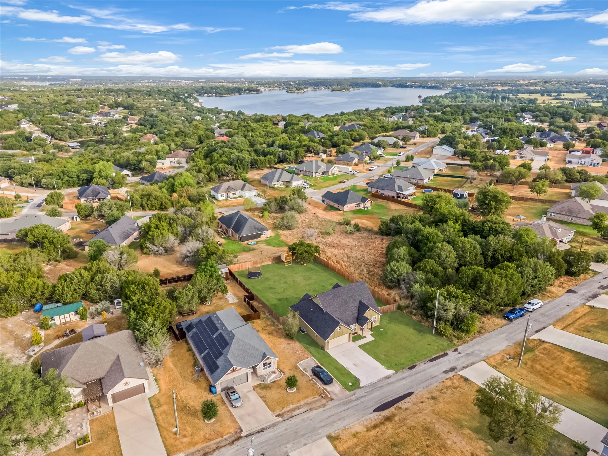 Aerial perspective featuring a residential street, established homes with gabled roofs, and mature trees