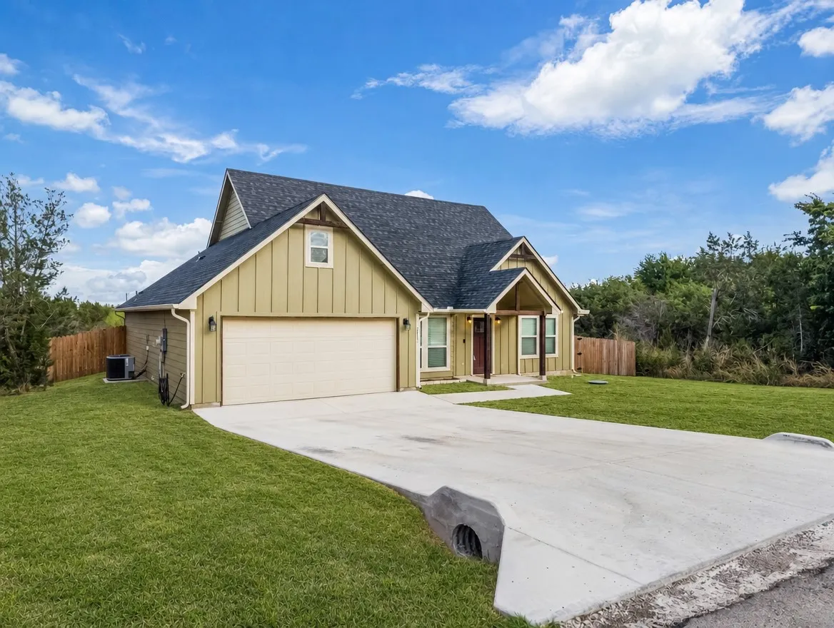 Board and batten siding, dark-shingle roof, covered entry, attached garage, and concrete driveway