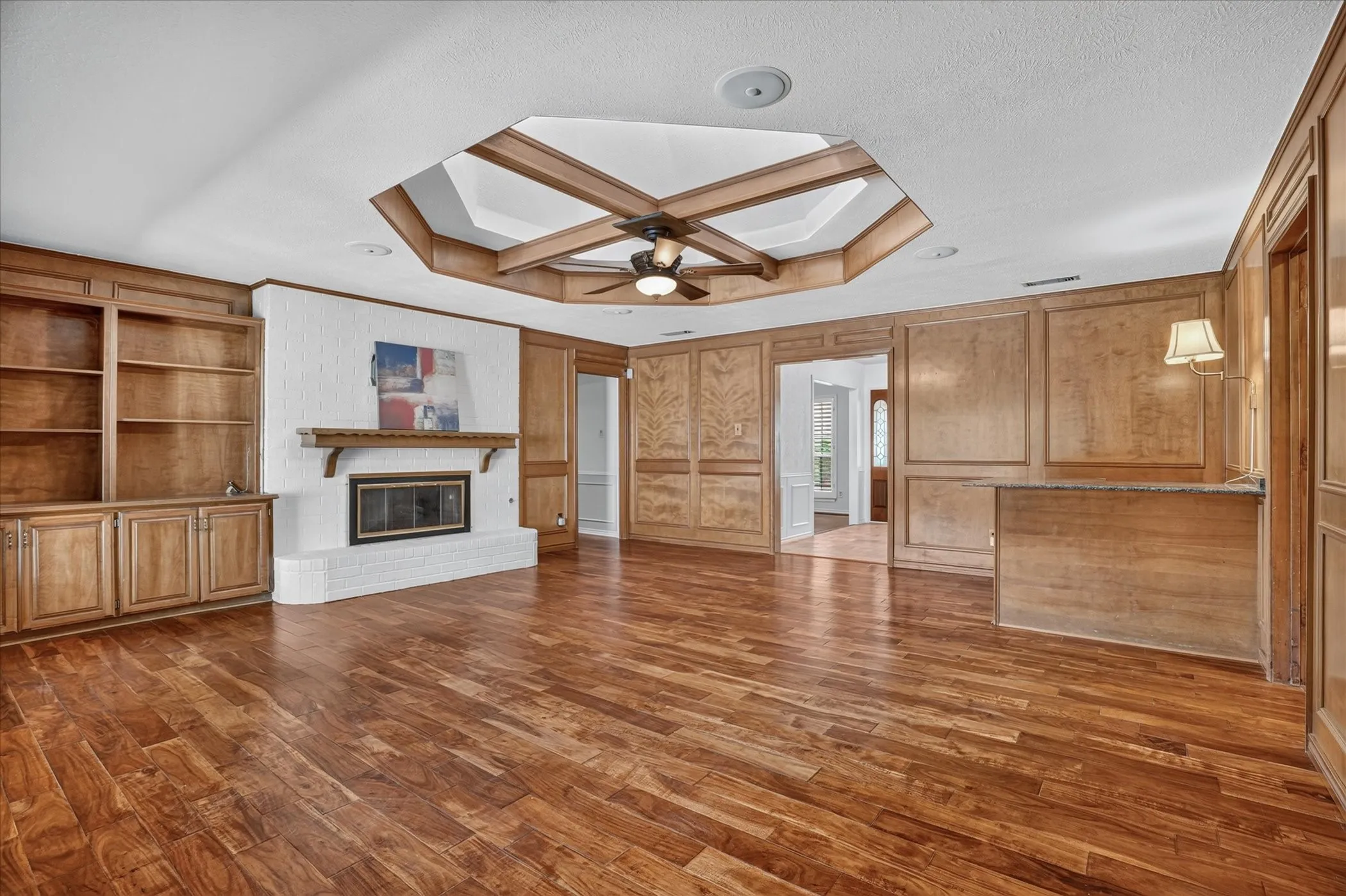 Living room with gorgeous wood floors, a unique skylight, and large windows with views to the backyard and pool
