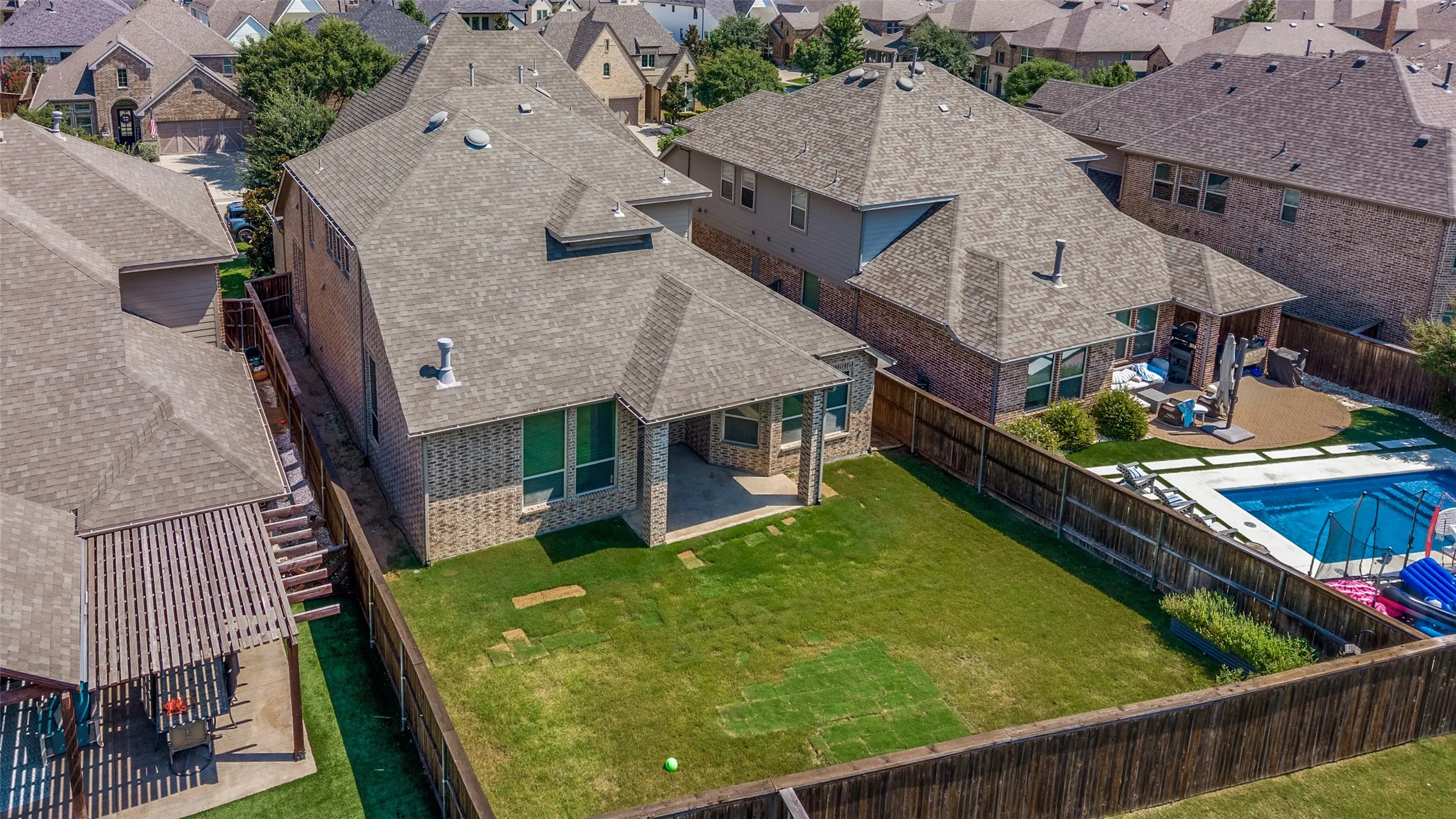 Expansive backyard featuring a rectangular swimming pool, concrete patio, covered patio space, and a wood privacy fence