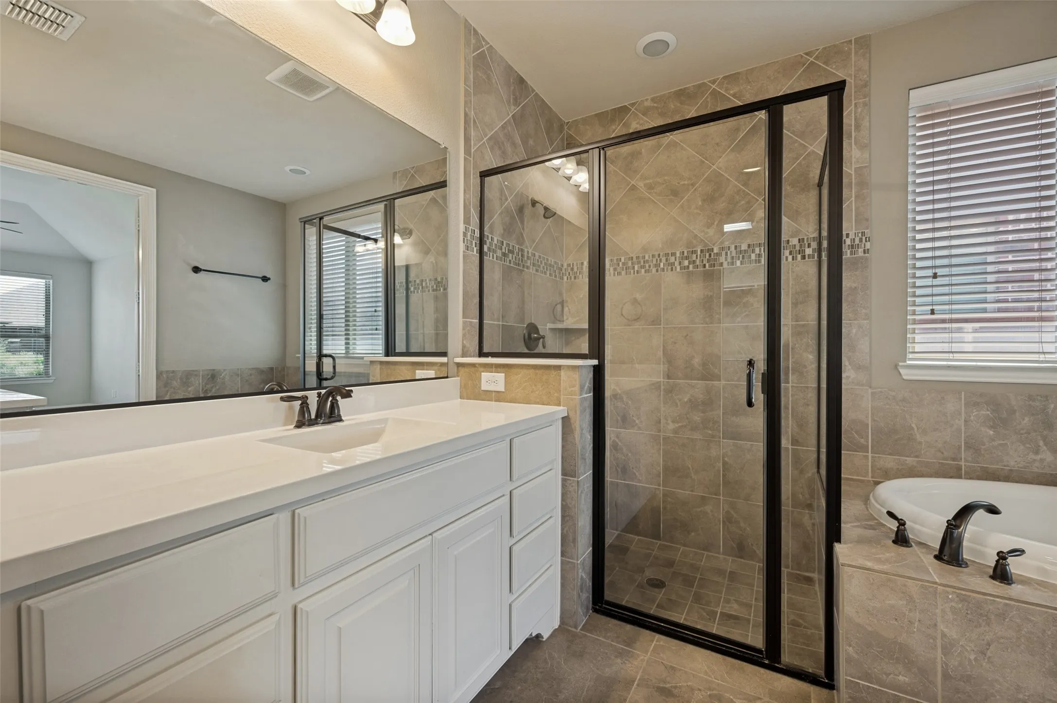 Spacious bathroom featuring a double vanity with white cabinetry and a light-colored countertop