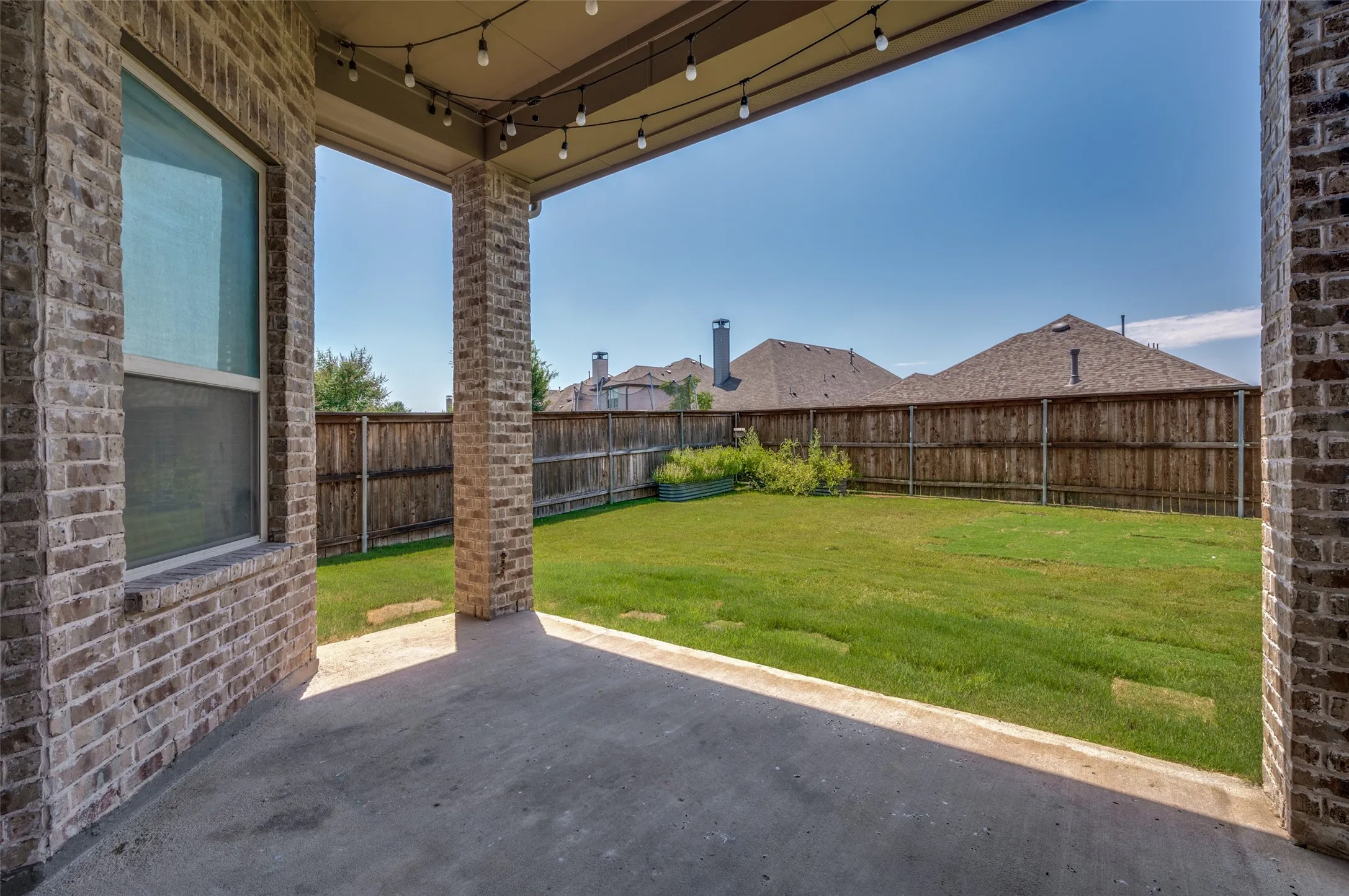 Covered patio featuring concrete flooring and brick support columns