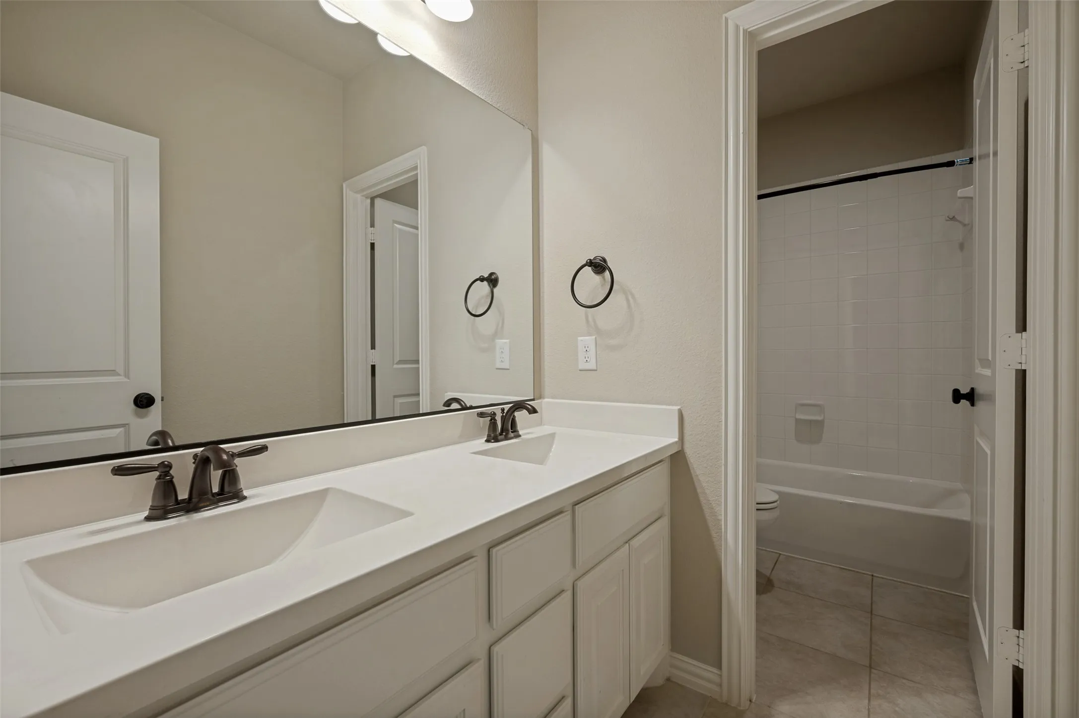 Bathroom featuring a dual vanity with integrated sinks and bronze-finish fixtures
