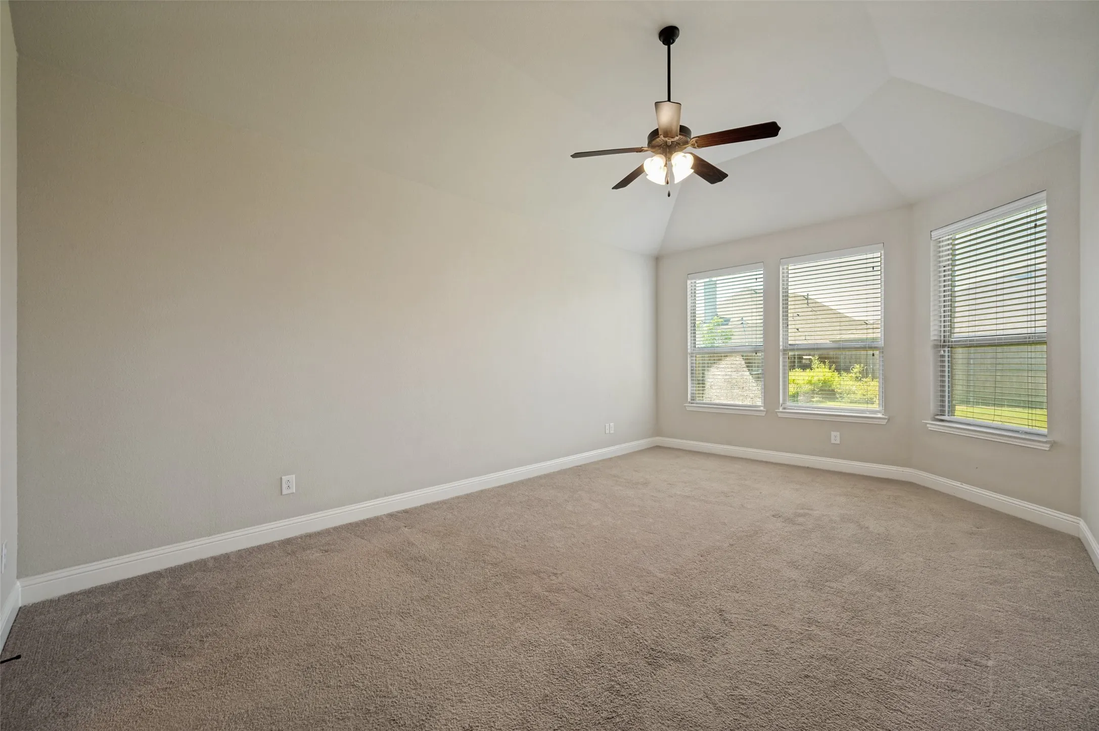 Spacious room featuring vaulted ceilings and a ceiling fan with integrated lighting