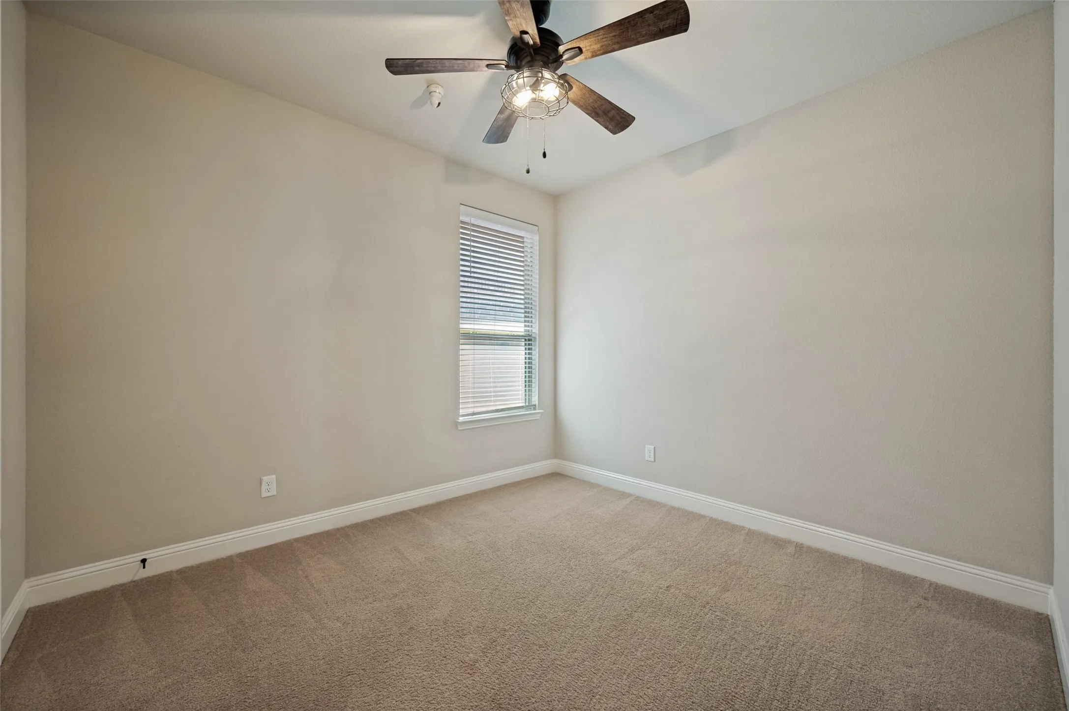 Carpeted room featuring neutral wall tones, a window with blinds, and a ceiling fan with light fixture