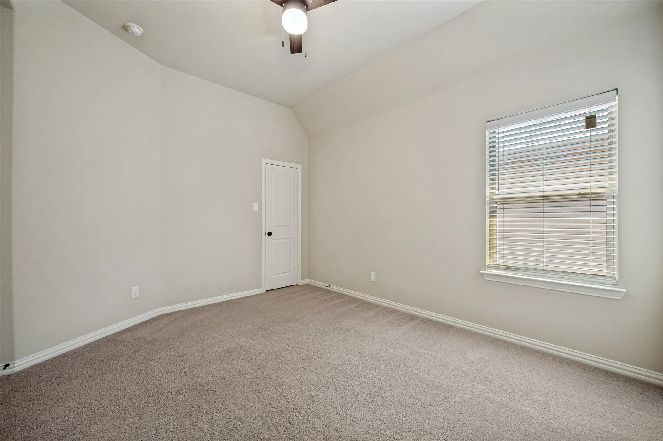 Spacious room featuring vaulted ceilings, neutral wall tones, and carpet flooring