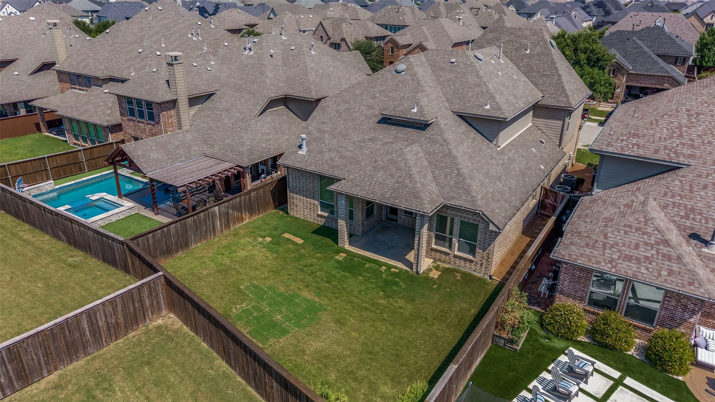 Backyard featuring a custom swimming pool with integrated spa, an adjacent covered pergola, a covered patio, and a manicured lawn