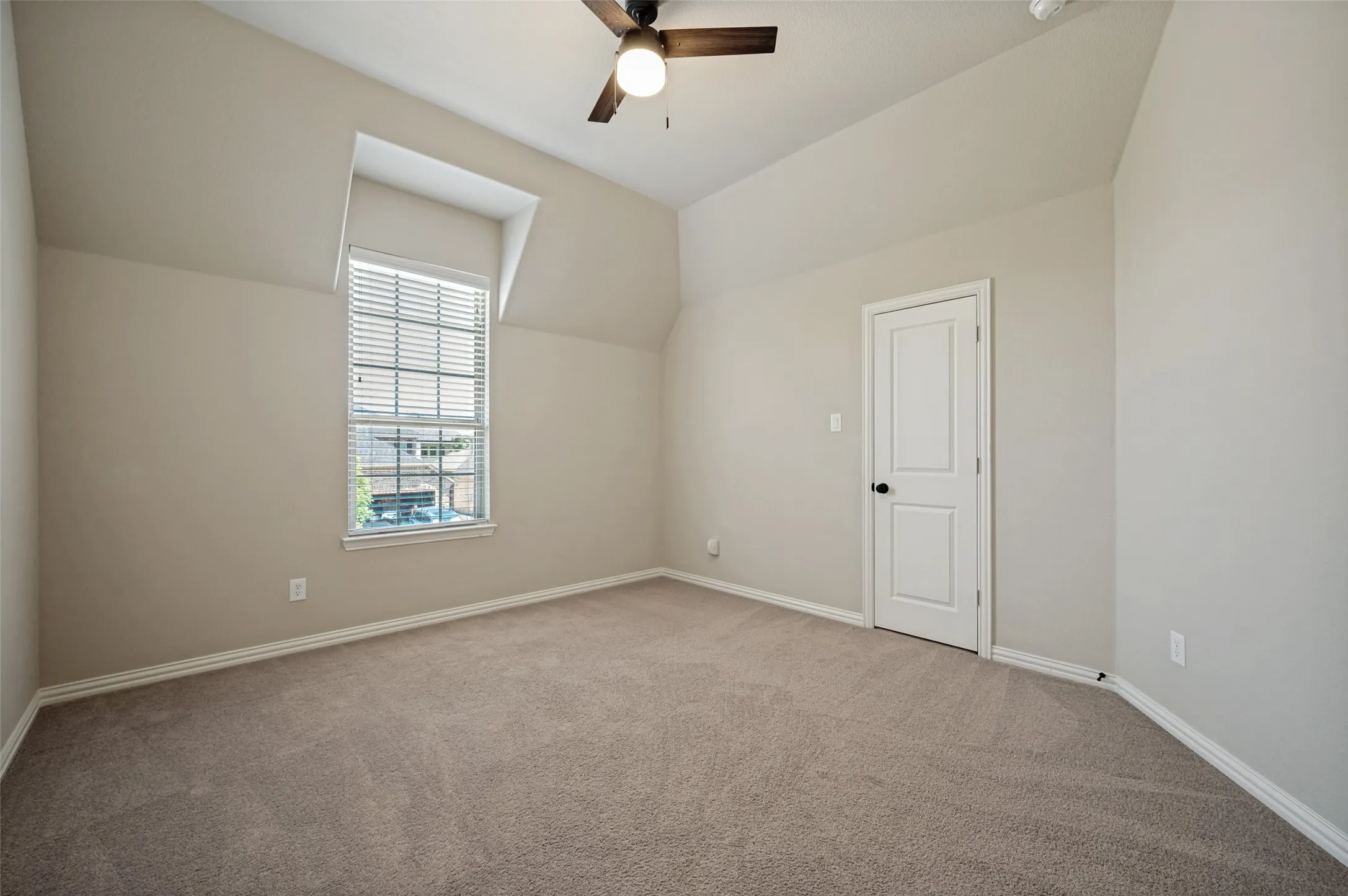 Carpeted room featuring a single window with blinds, a ceiling fan with integrated lighting, and a paneled interior door