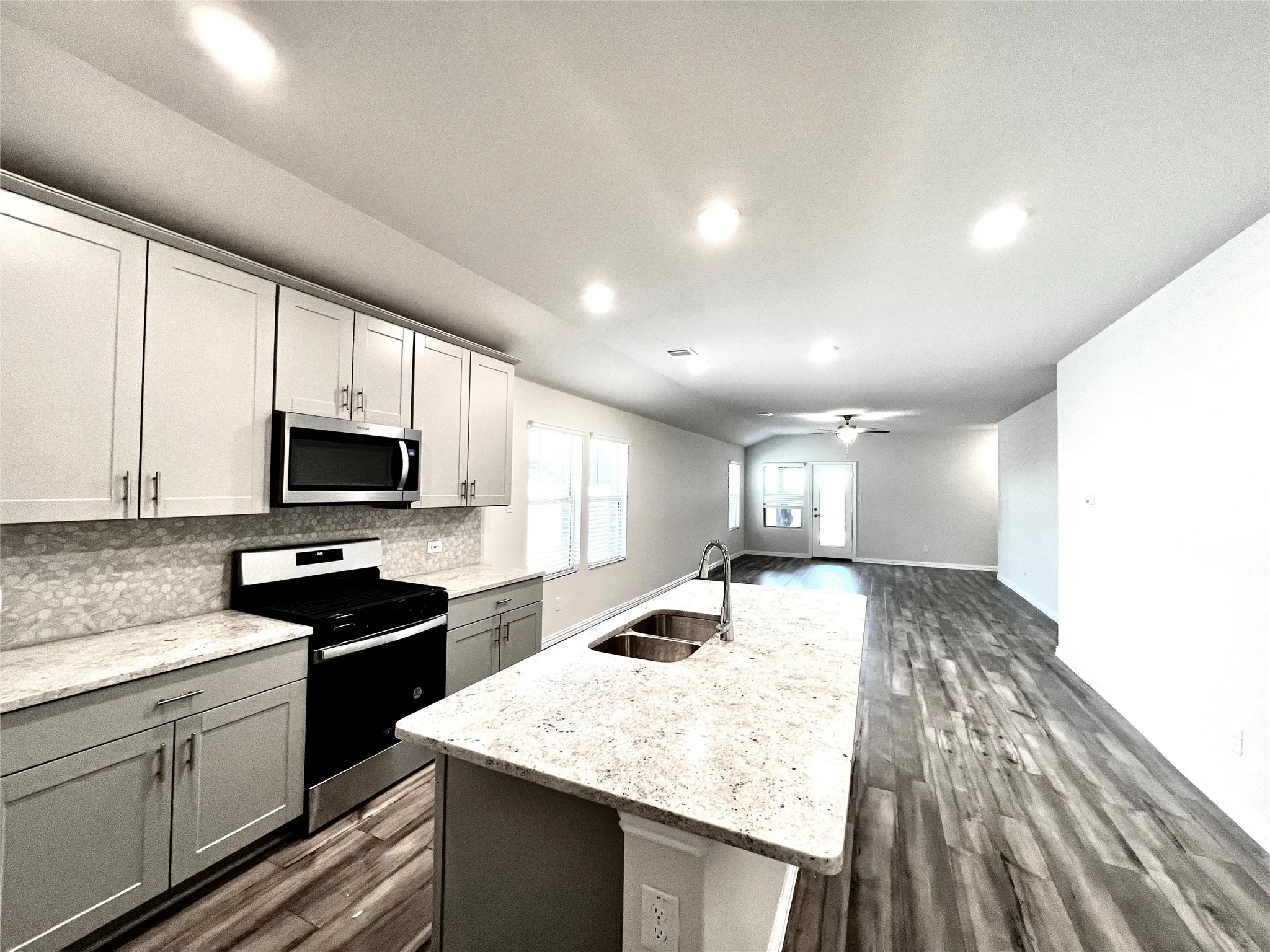 Kitchen featuring light gray cabinetry, stainless steel appliances, granite countertops, and a double basin sink