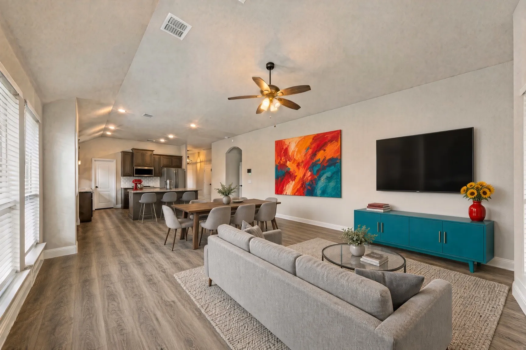 Open-concept living space with wood-finish flooring, vaulted ceilings, recessed lighting, and a ceiling fan
