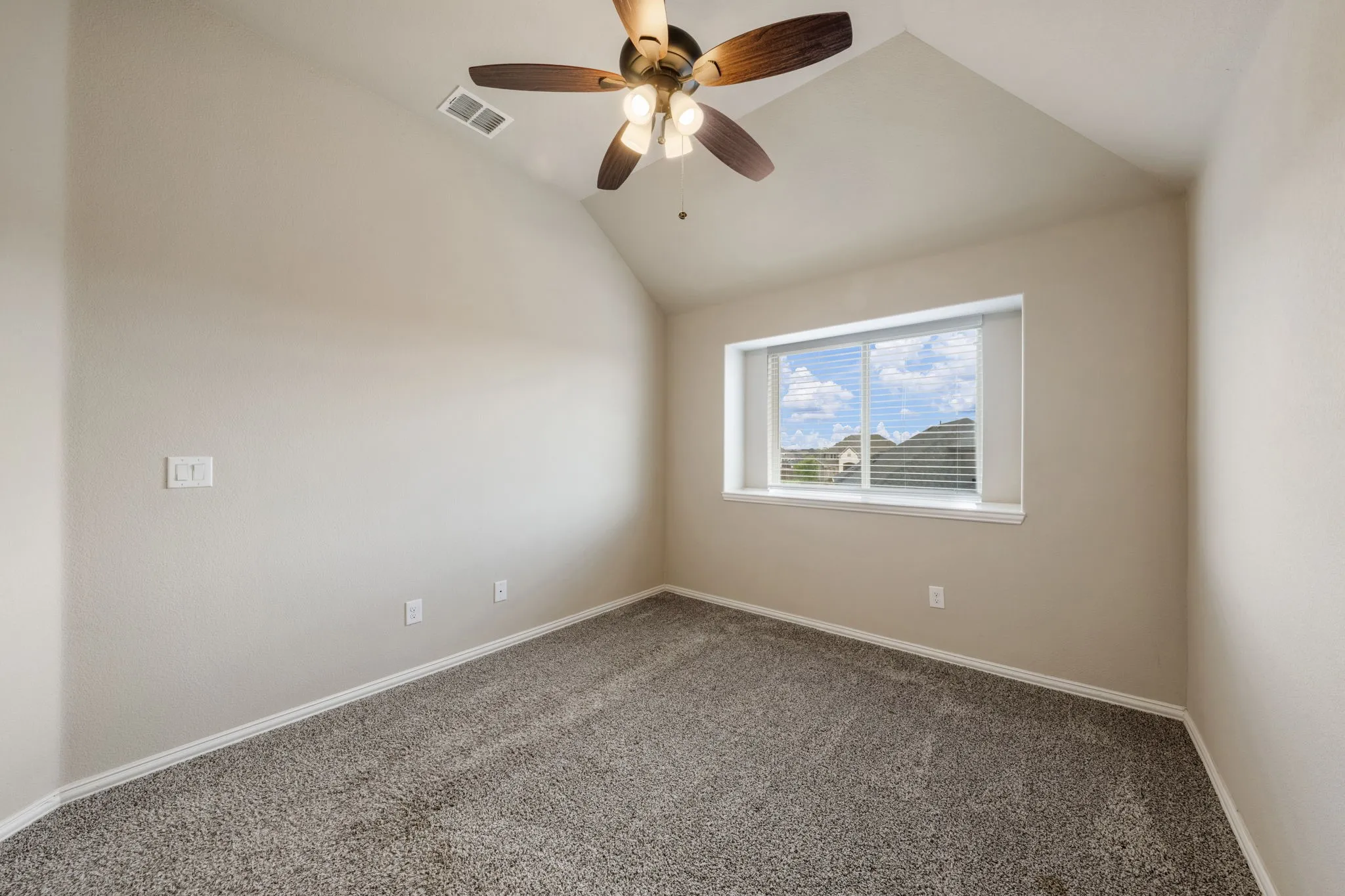 Carpeted room featuring a ceiling fan with light fixture and a window with blinds