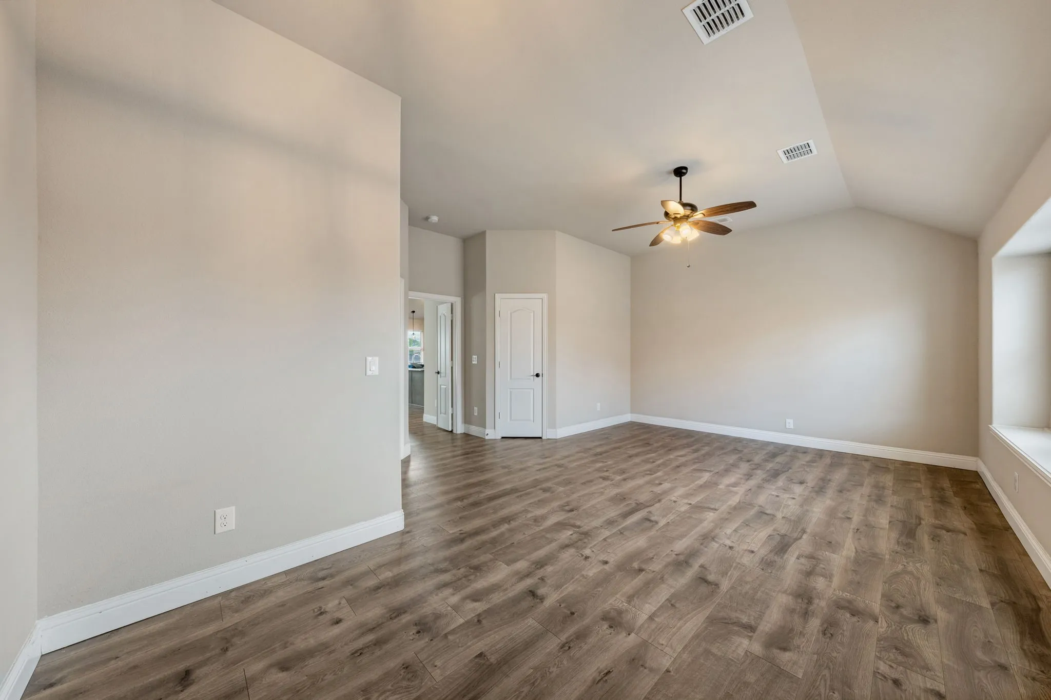 Vaulted ceilings, wood-finish flooring, a built-in window bench, and a ceiling fan