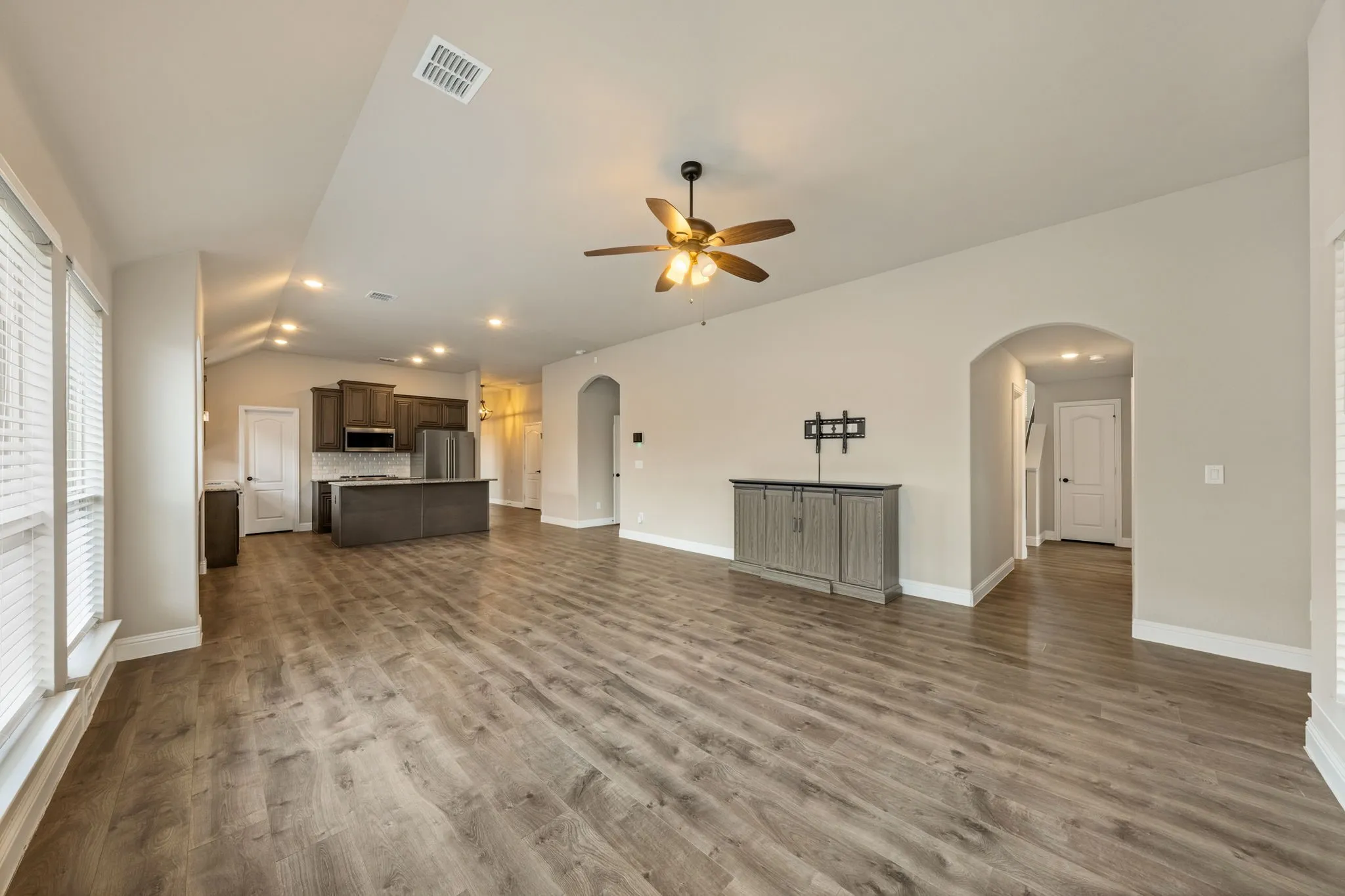 Wood-finish flooring throughout, a ceiling fan with integrated lighting, and arched doorways