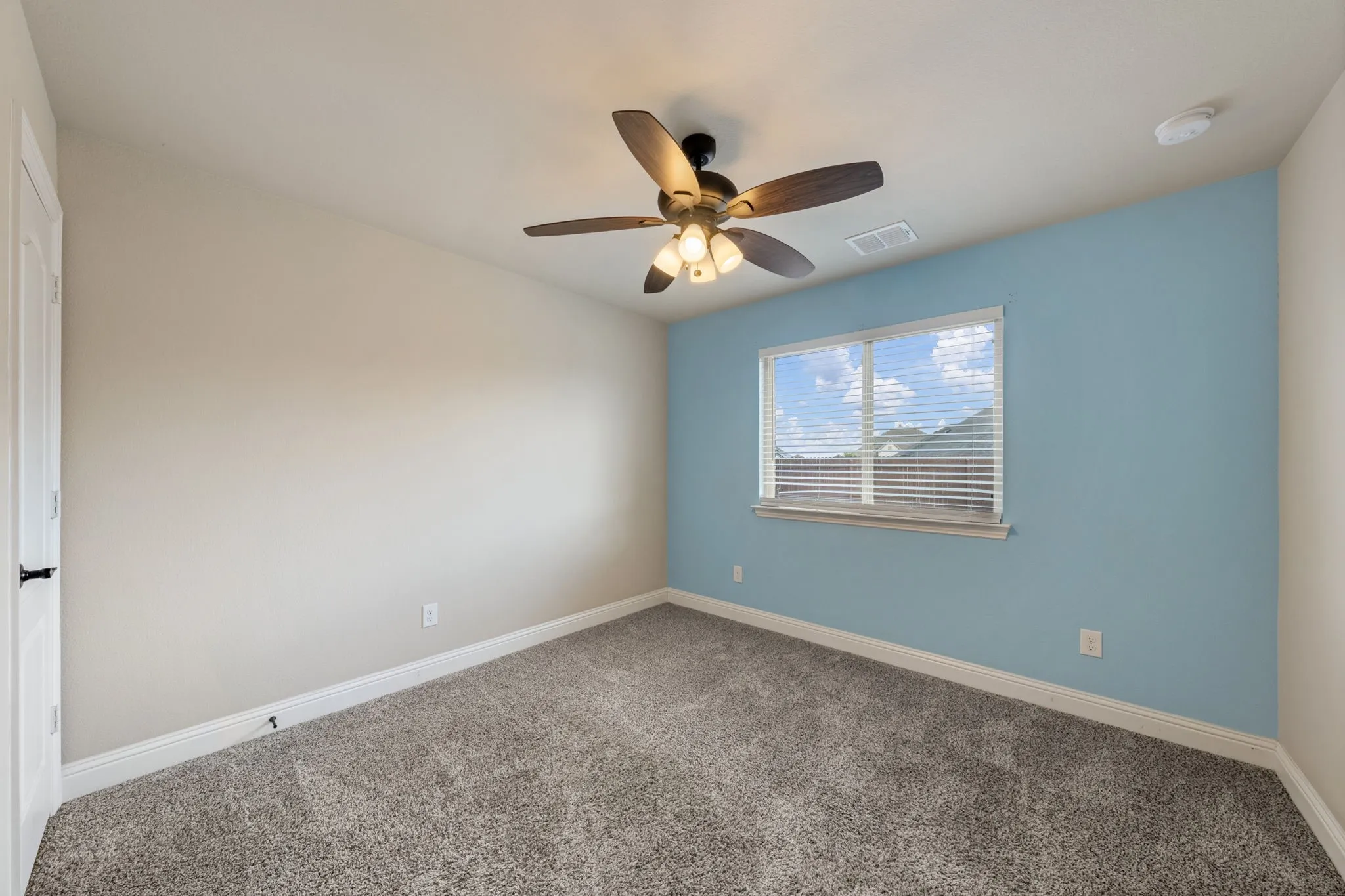Room featuring soft-pile carpet flooring, a window with horizontal blinds, a ceiling fan with integrated lighting, and a white interior door