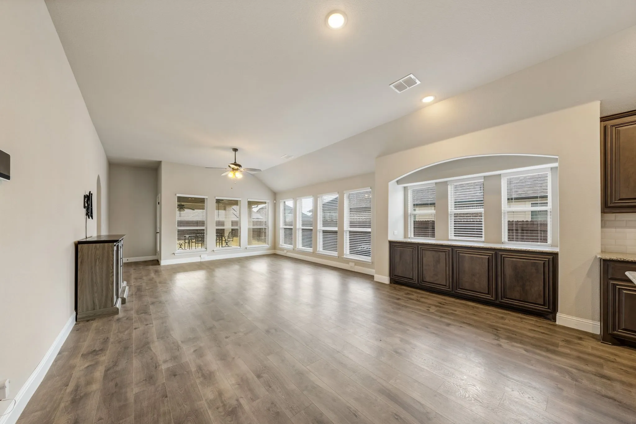Open-concept living space with wood-finish flooring, vaulted ceilings, and recessed lighting