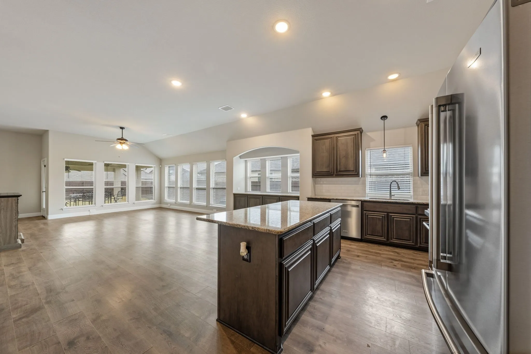 Spacious room featuring wood-finish flooring, recessed lighting, and ample natural light through multiple windows