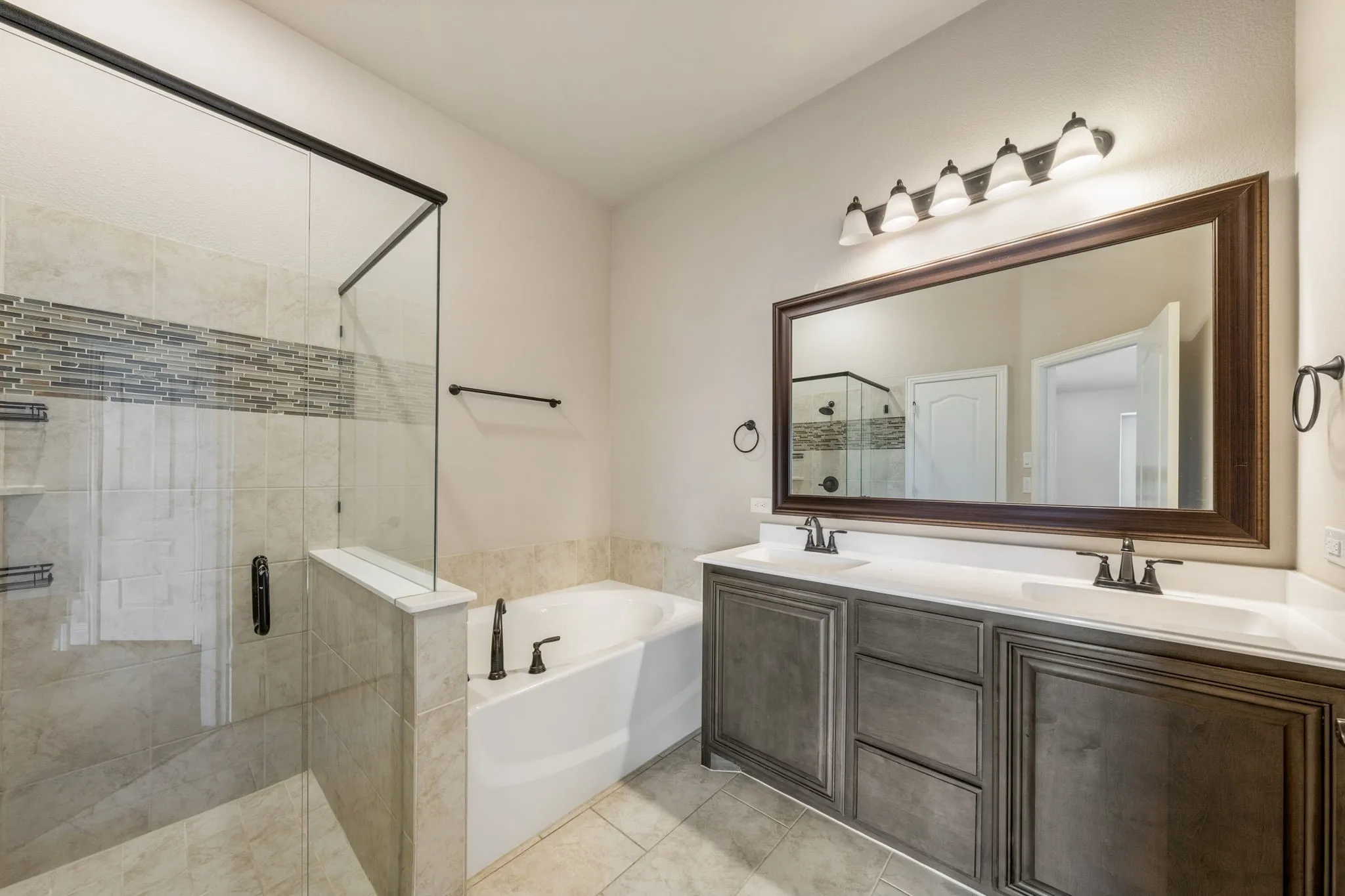 Dual vanity with white countertops, dark wood-finish cabinetry, and a large framed mirror